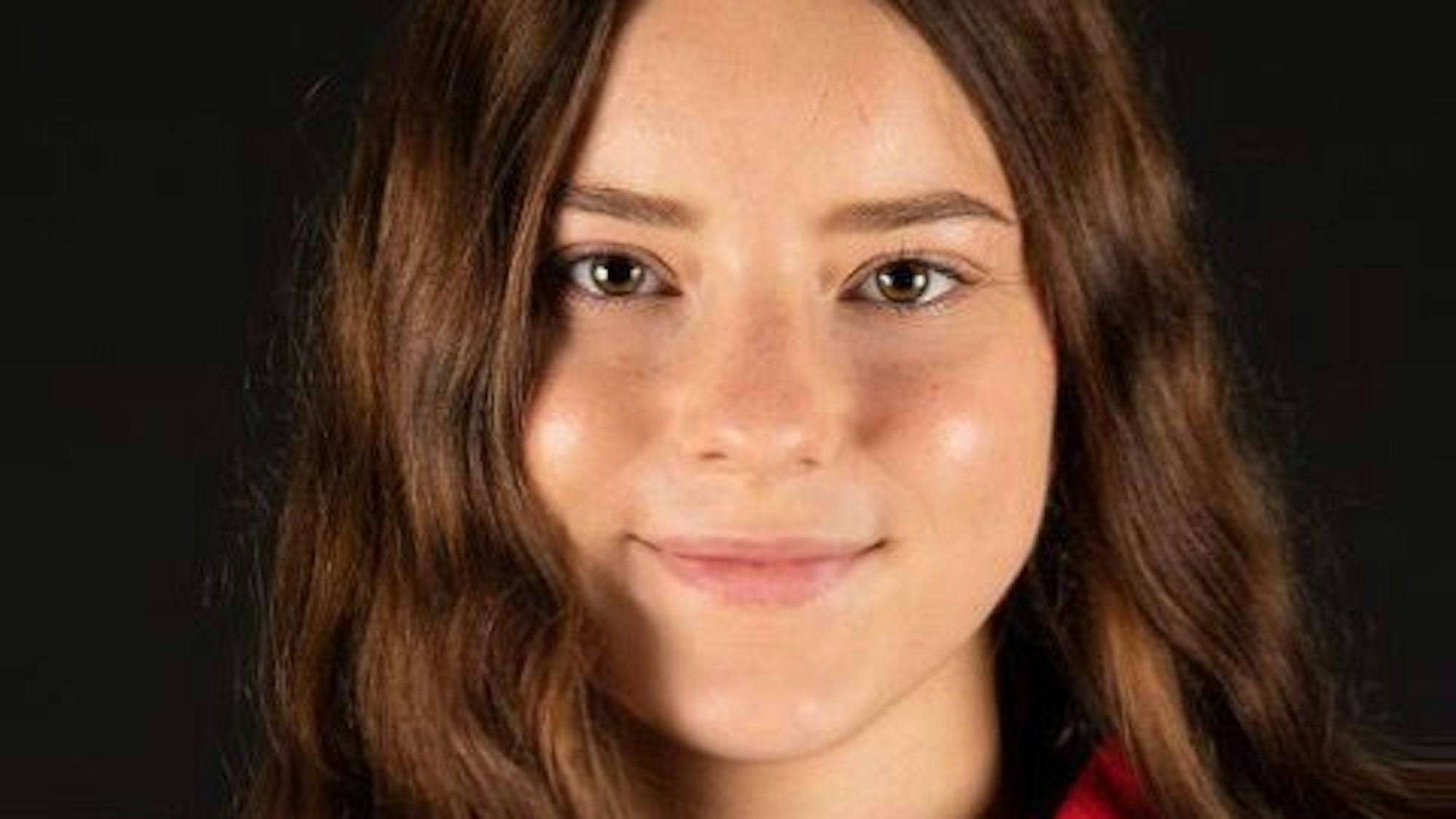 Lea Badura guckt in die Kamera. Sie hat lange braune Haare und trägt ein Eishockey-Trikot.