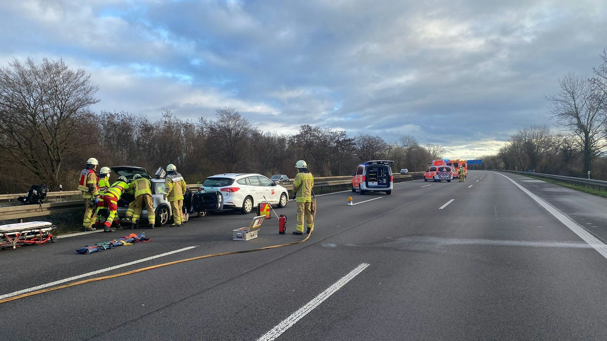 Zwei Fahrzeuge stehen am linken Fahrbahnrand. Rettungskräfte arbeiten am Kofferraum.