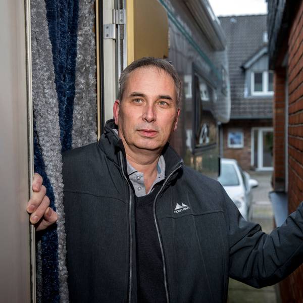 Wolfgang Stier steht zwischen zwei Häusermauern und hat seine linke Hand an den Backstein gelegt. Er trägt eine dunkle Adidas-Jacke, darunter ein Hemd und schwarzen Pullover. Er hat kurze, graue Haare.