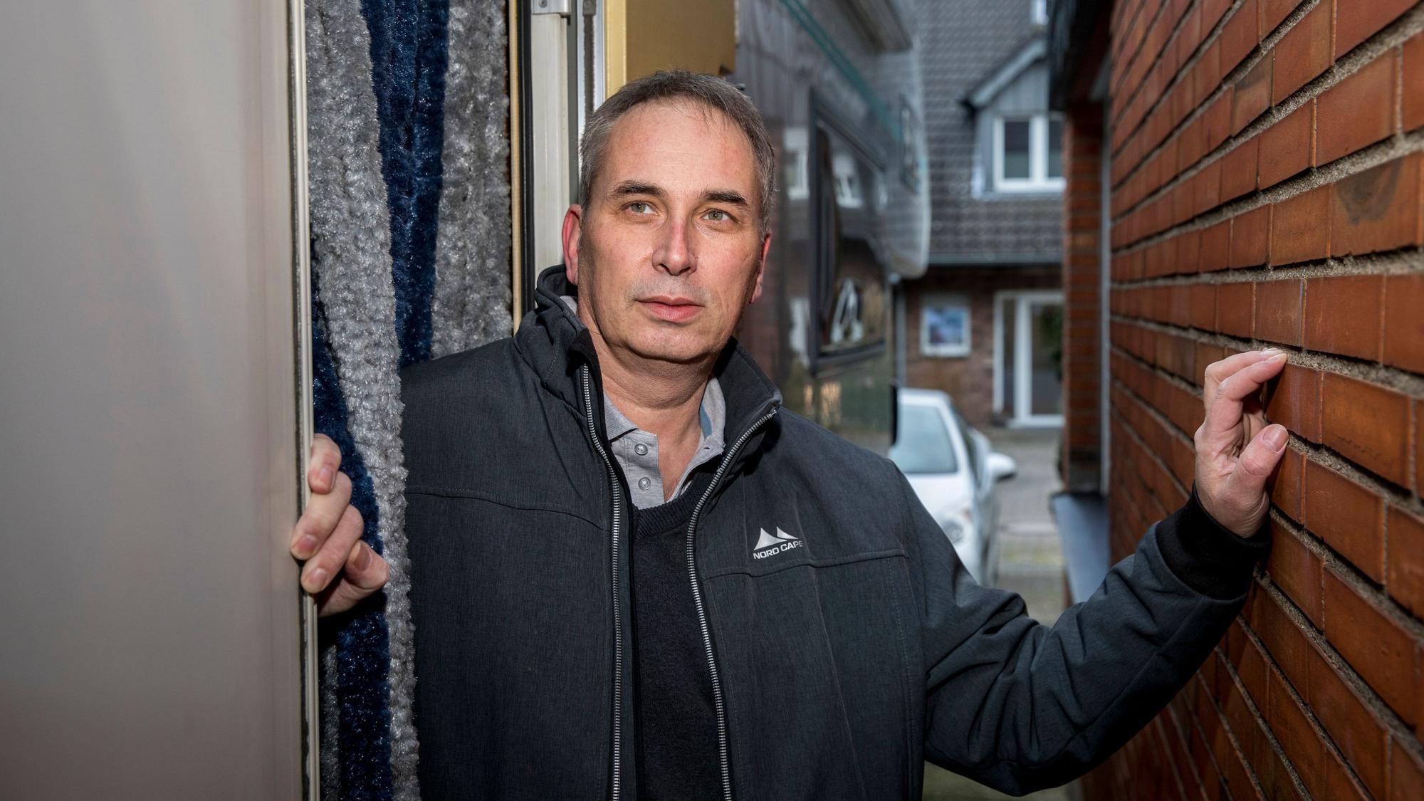 Wolfgang Stier steht zwischen zwei Häusermauern und hat seine linke Hand an den Backstein gelegt. Er trägt eine dunkle Adidas-Jacke, darunter ein Hemd und schwarzen Pullover. Er hat kurze, graue Haare.