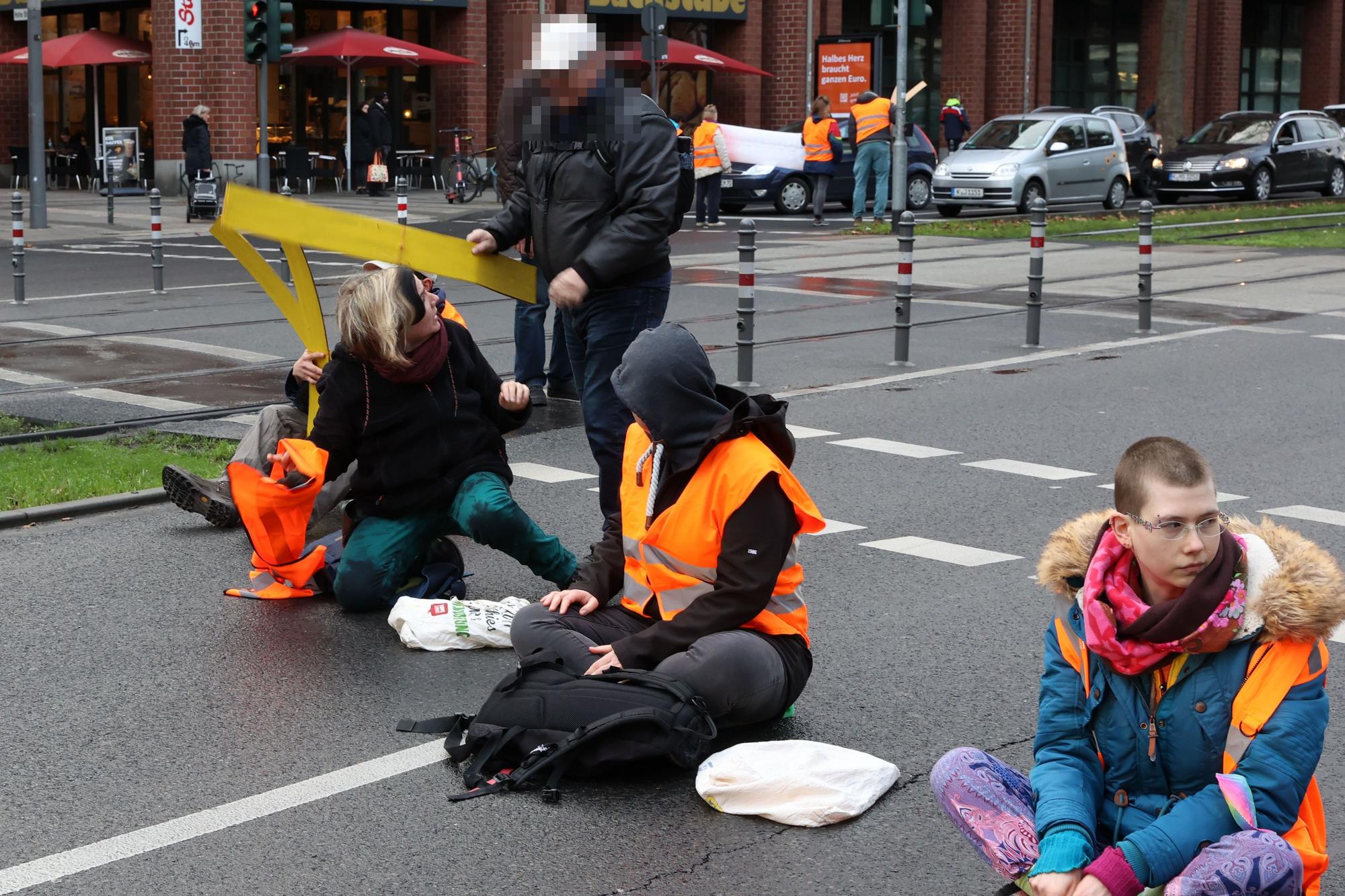 Ein Passant versucht, Aktivisten der "Letzten Generation" ihre Utensilien abzunehmen.