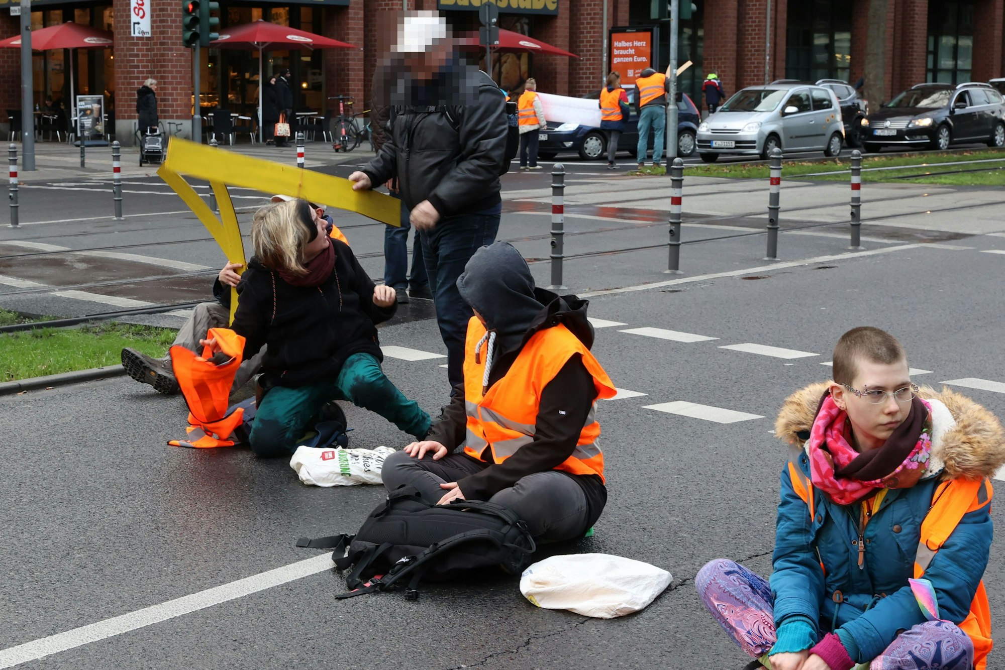 Ein Passant versucht, Aktivisten der "Letzten Generation" ihre Utensilien abzunehmen.