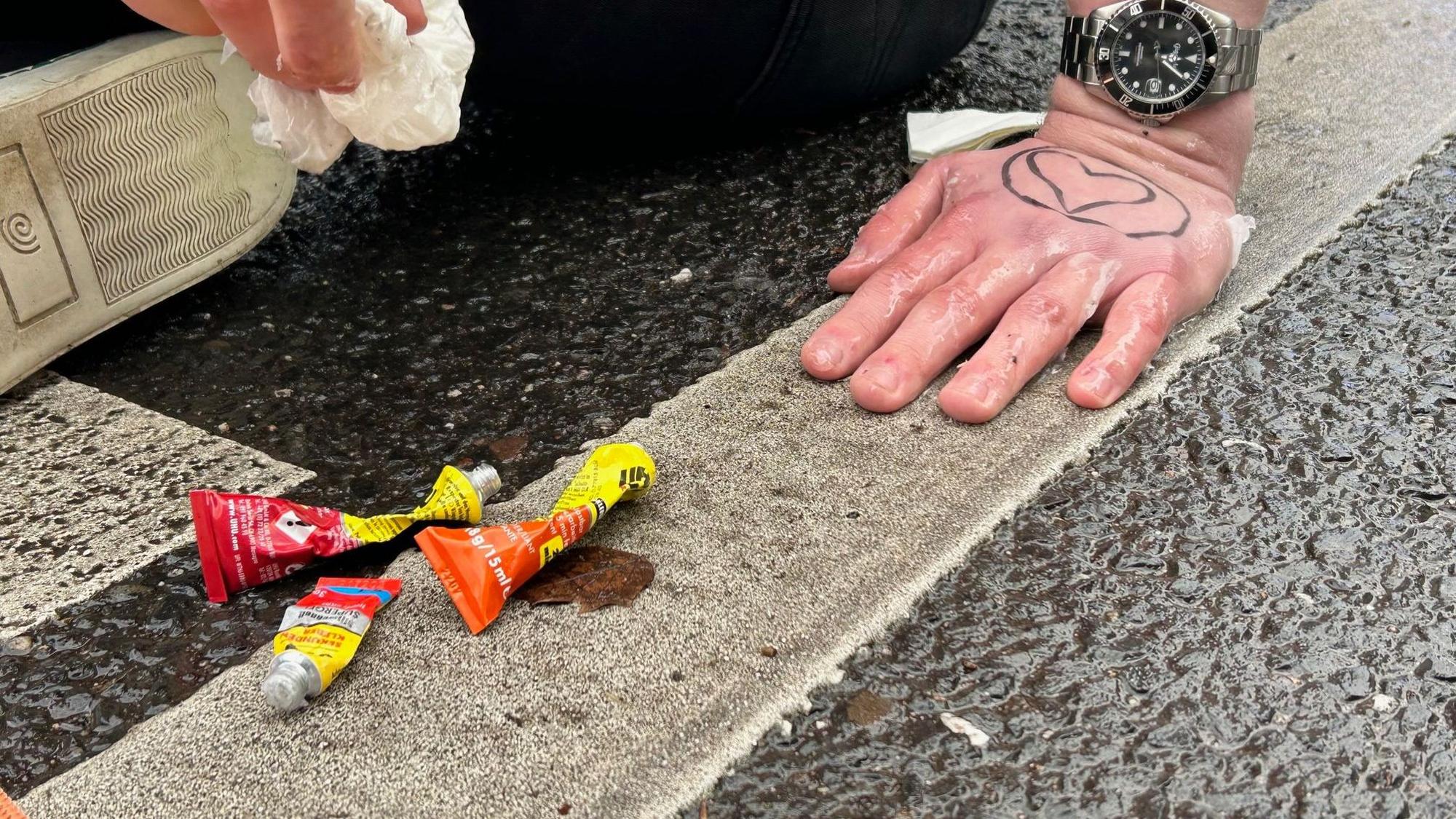 Drei Tuben Sekundenkleber liegen neben einer an die Fahrbahn geklebten Hand eines Klima-Demonstranten am 6. Januar auf der Cäcilienstraße.
