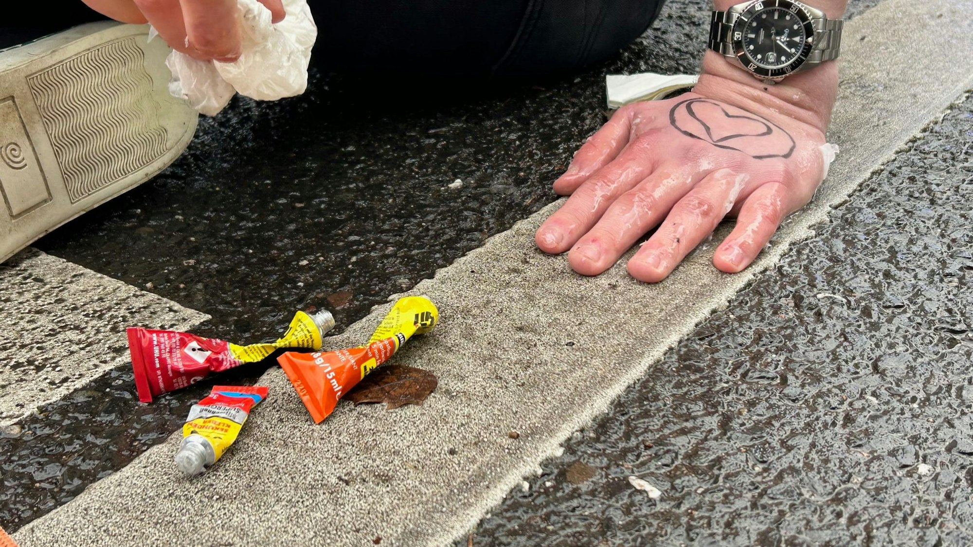 Drei Tuben Sekundenkleber liegen neben einer an die Fahrbahn geklebten Hand eines Klima-Demonstranten am 6. Januar auf der Cäcilienstraße.