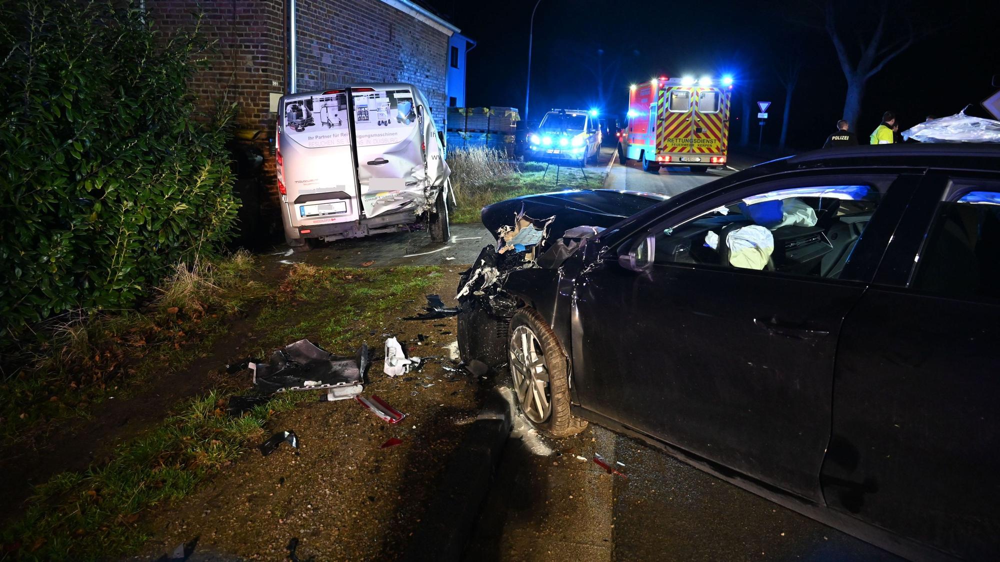 Unfallstelle in Kerpen. Zu sehen sind beide involvierten Fahrzeuge, ein schwarzer Audi hat einen frotalen Schaden, ein silberner Transporter ist hinten rechts beschädigt. Im Hintergrund Polizei- und Rettungswagen mit Blaulicht.
