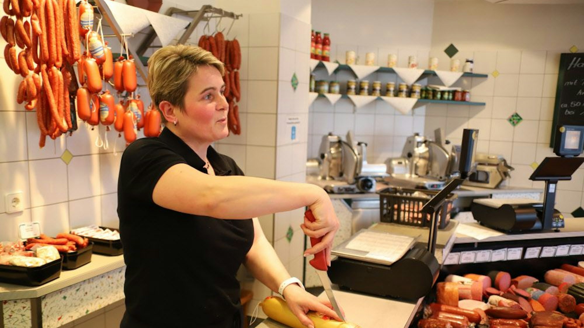 Eine Metzgerin steht an der Ladentheke ihrer Metzgerei.
