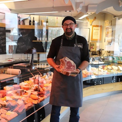 Ein Metzger steht vor seiner Ladentheke.