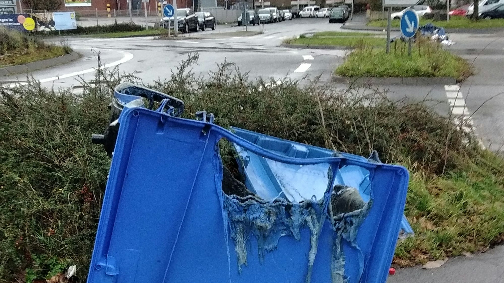 Ein ausgebrannter Altpapiercontainer steht an einem Kreisverkehr in Leverkusen-Steinbüchel auf dem Fußweg.