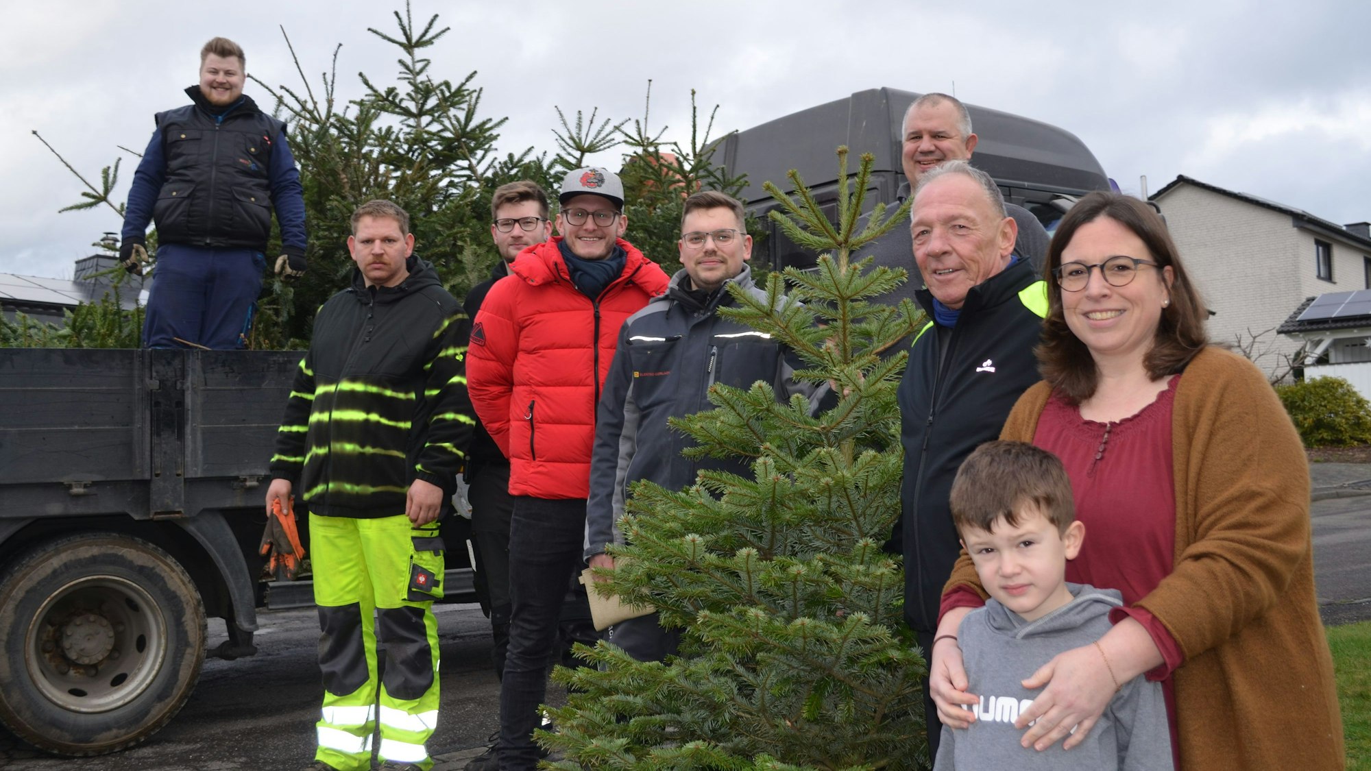 Eine Gruppe Müllenbacher vor einem Anhänger mit ausgedienten Weihnachtsbäumen.