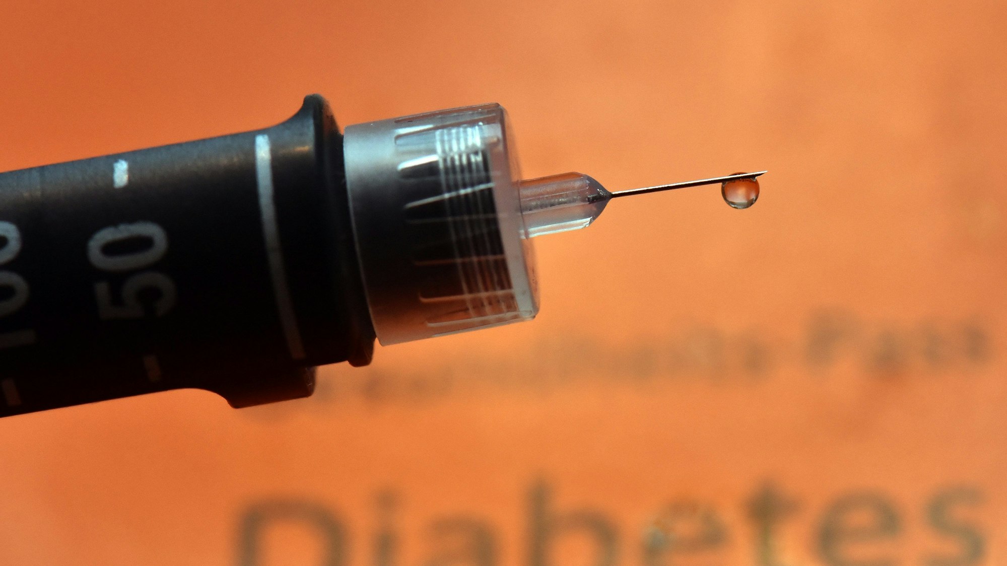 Ein Tropfen Insulin hängt an der Nadel einer wiederverwendbaren Spritze, einem sogenannten Pen, für Diabetiker.