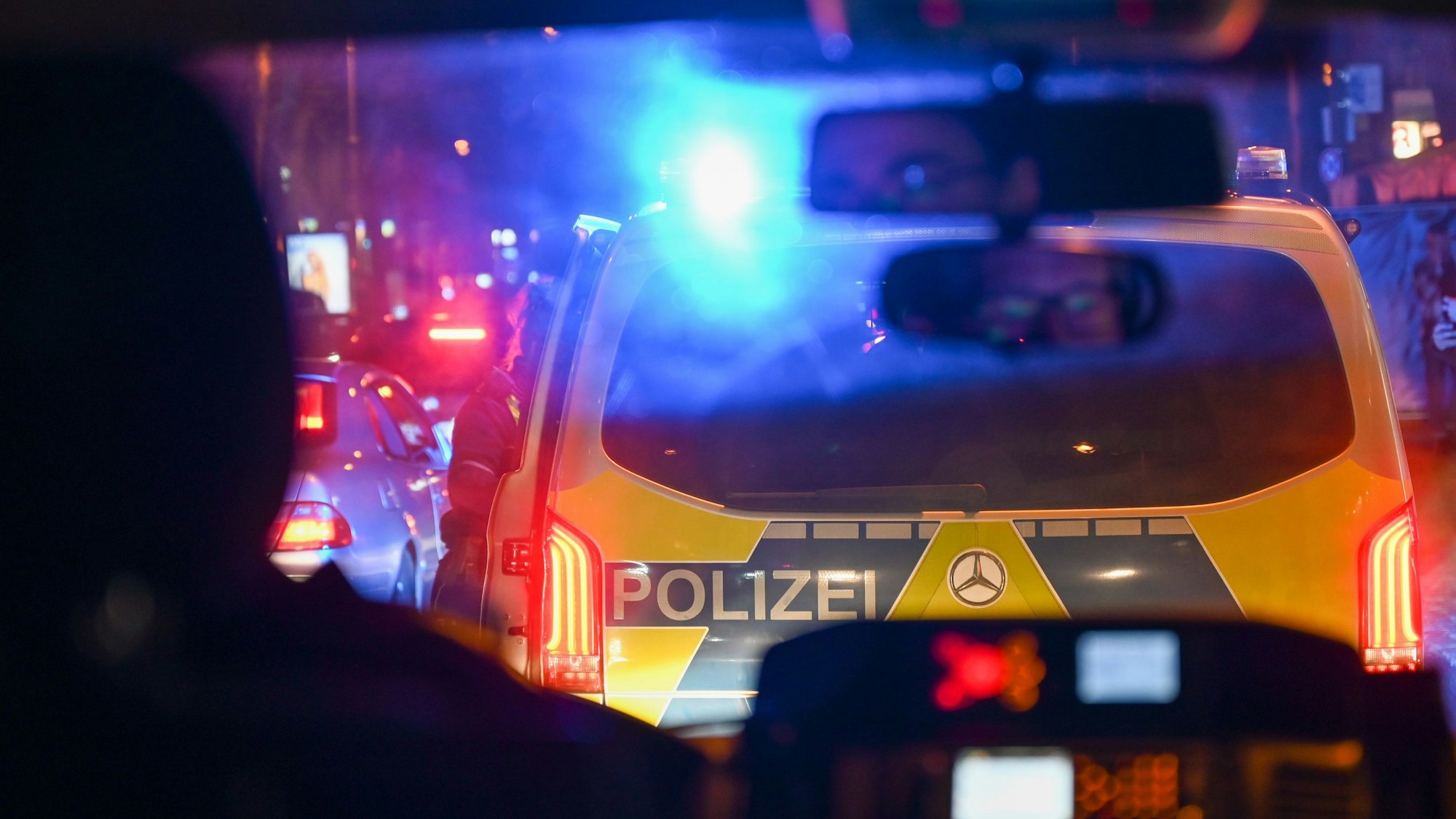 Blick durch die Frontscheibe auf das Heck eines weiteren Polizeiautos mit eingeschaltetem Blaulicht.