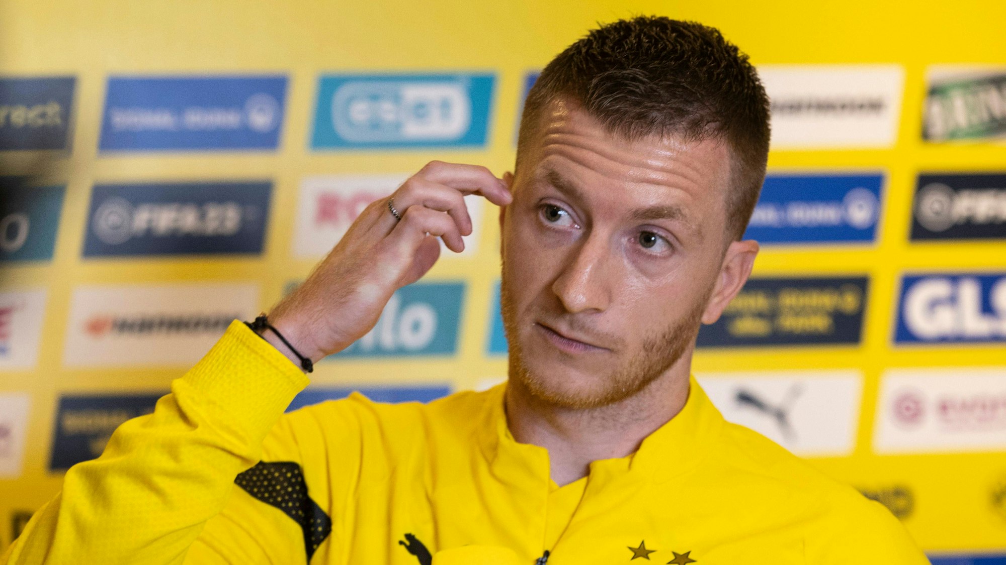 Marco Reus fasst sich bei einer Medienrunde mit Journalisten an die Wange.