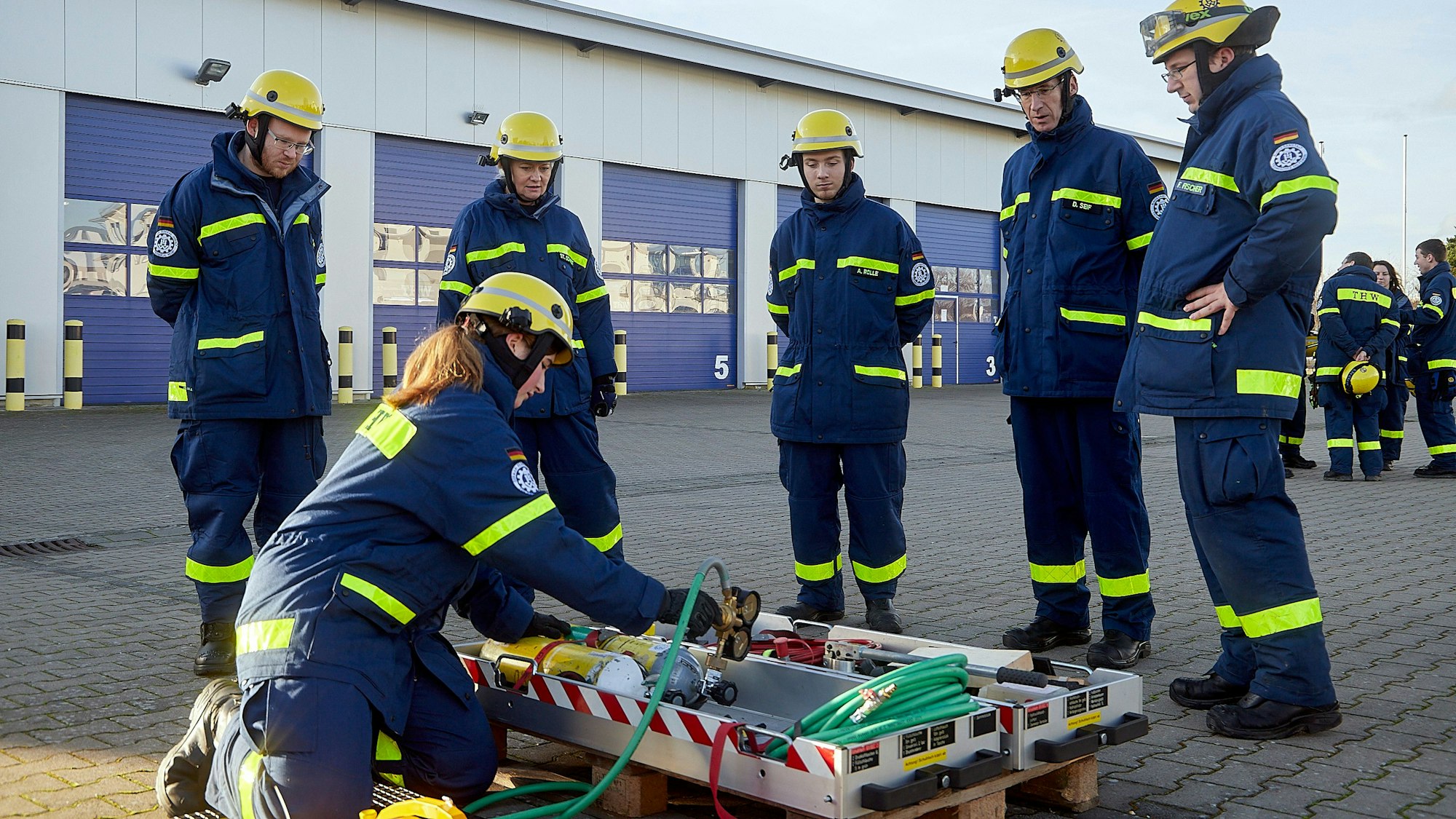 Eine THW-Helferin führt den Auszubildenden Arbeitsgeräte vor.