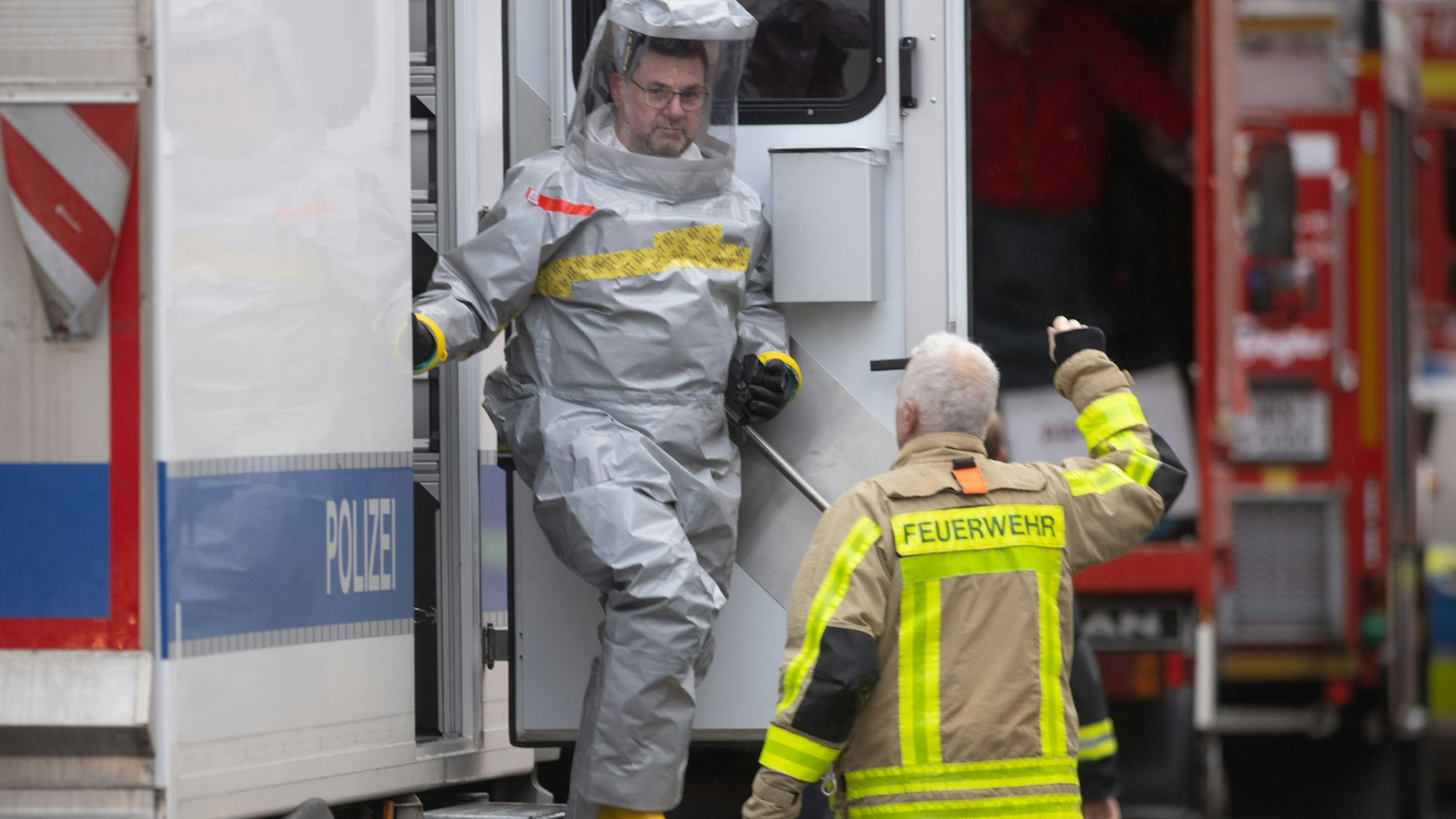 Ein Spezialist der Polizei im Schutzanzug kommt zu seinem Einsatz aus einem Fahrzeug. Ein Iraner soll einen Giftanschlag geplant haben. Der 32-Jährige und sein Bruder waren in der Nacht zum Sonntag bei einem Großeinsatz der Polizei festgenommen worden.