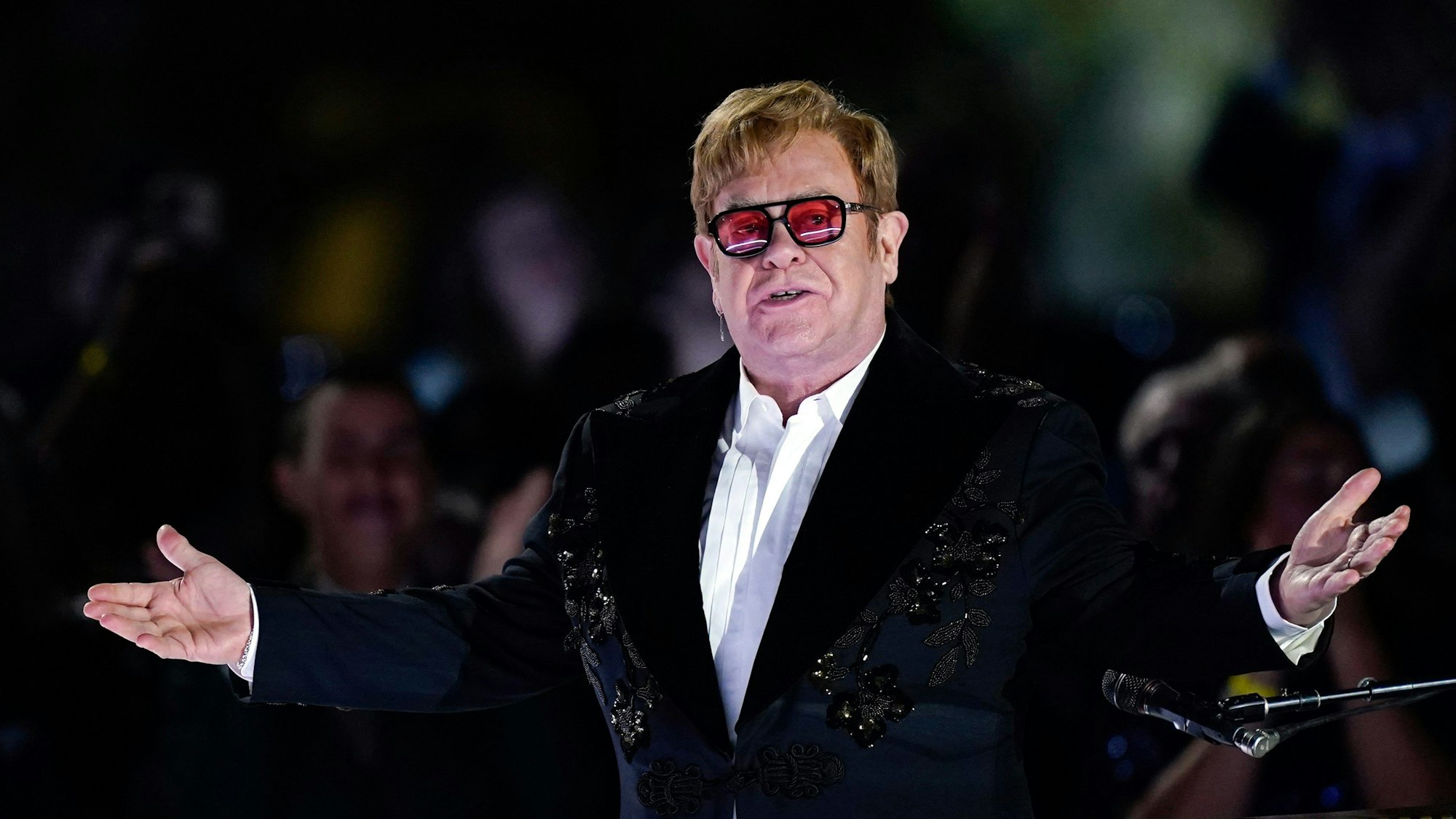Der britische Sänger Elton John bei einem Auftritt auf dem Südrasen des Weißen Hauses. Er trägt ein schwarzes Jackett über einem weißen Hemd und eine Brille mit roten Gläsern.