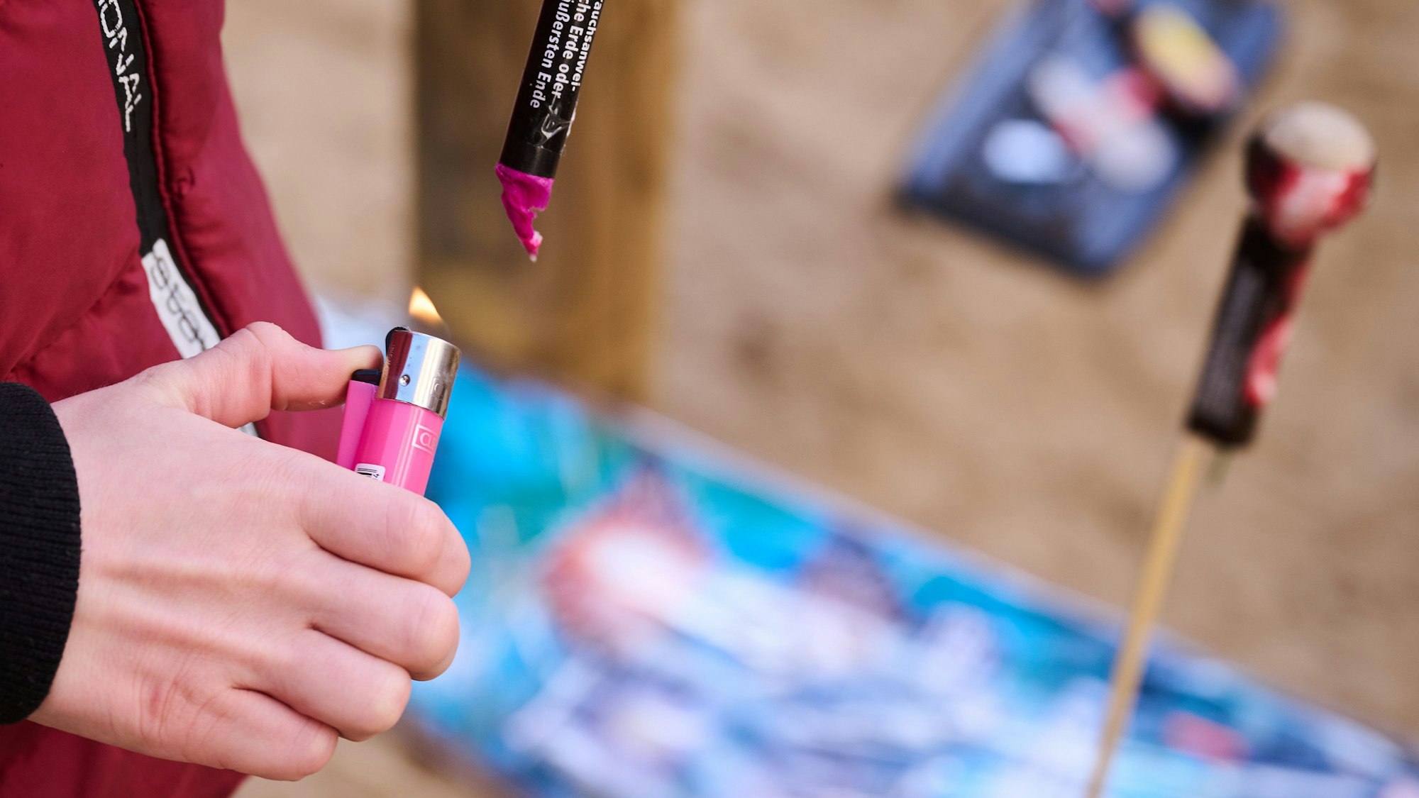 Eine Hand mit einem Feuerzeug zündet einen Böller.