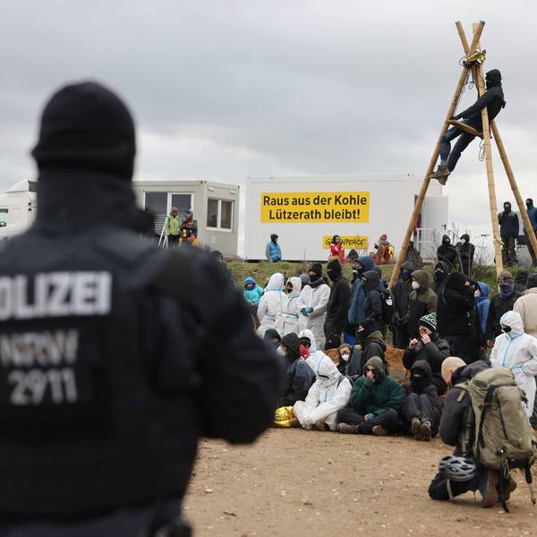 Ein Polizist beobachtet Klimaschutzaktivisten, die am Rand des Tagebaus sitzen. Das Dorf Lützerath soll zur Erweiterung des Braunkohletagebaus Garzweiler II abgebaggert werden.