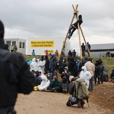 Ein Polizist beobachtet Klimaschutzaktivisten, die am Rand des Tagebaus sitzen. Das Dorf Lützerath soll zur Erweiterung des Braunkohletagebaus Garzweiler II abgebaggert werden.