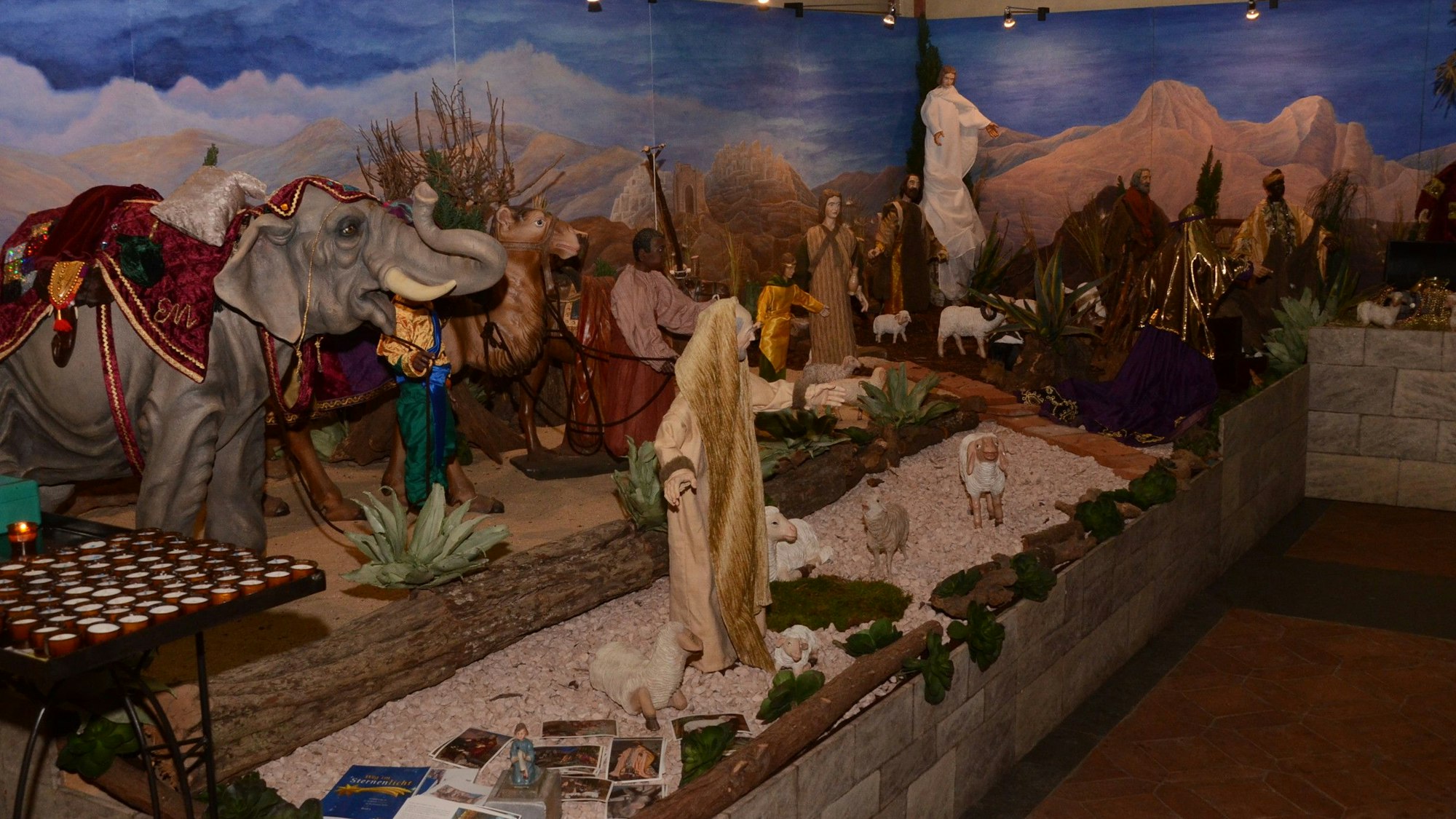 Krippe in St. Bartholomäus Wahlscheid vor gemalter Szenerie im Hintergrund.