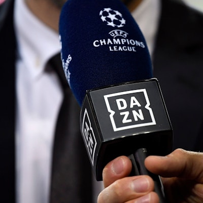 Ein Reporter hält ein Mikrofon des Streamingdienstes DAZN während eines Interviews fest. (Symbolbild)