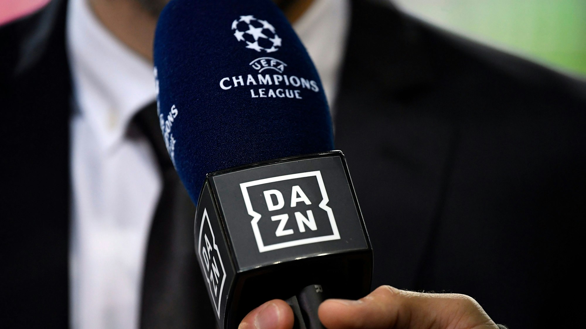 Ein Reporter hält ein Mikrofon des Streamingdienstes DAZN während eines Interviews fest. (Symbolbild)
