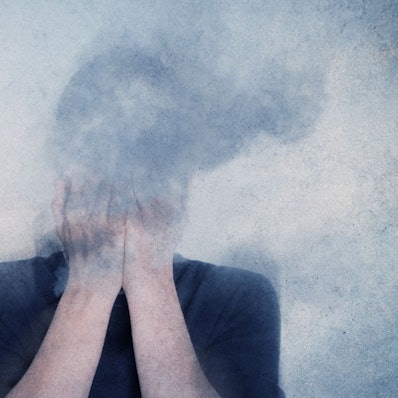 Der Kopf eines jungen Menschen ist umhüllt von Rauch, er oder sie hält die Hände vor das Gesicht.