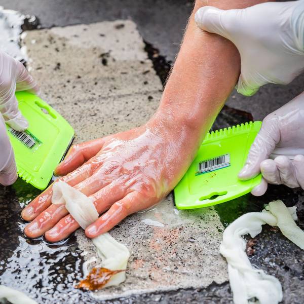 Die Hand eines Klimaaktivisten wird von Polizisten vom Boden versucht zu lösen.