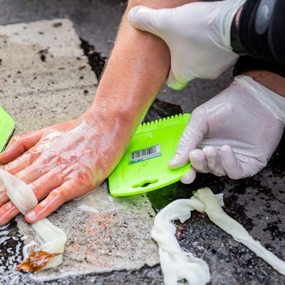 Die Hand eines Klimaaktivisten wird von Polizisten vom Boden versucht zu lösen.