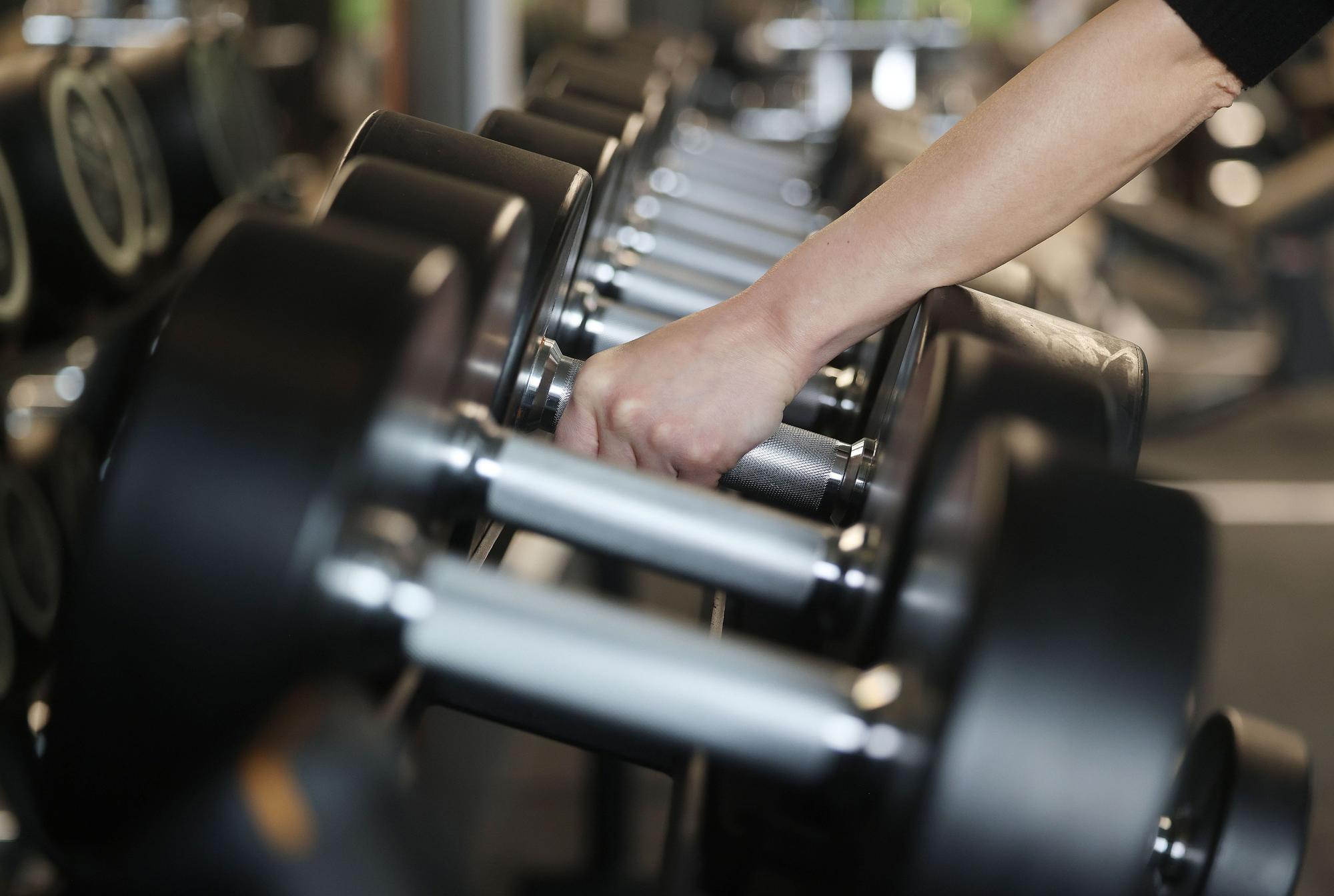 Eine Frau nimmt Hanteln in einem Fitnessstudio.