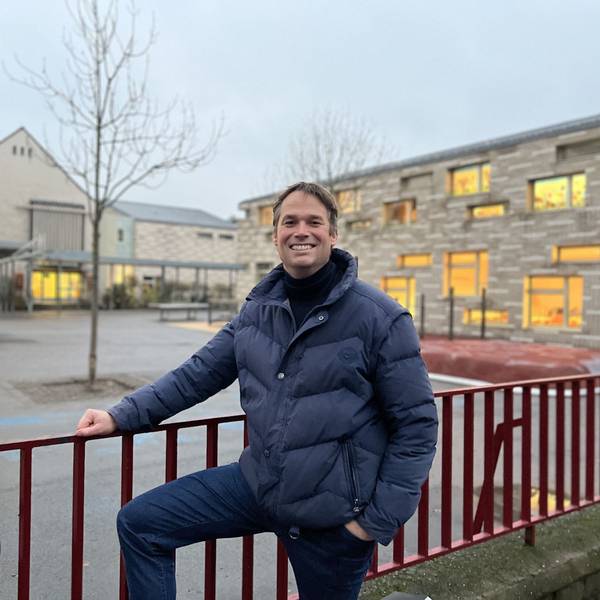 Thomas Heidbrink, der Schulpflegschaftsvorsitzender der GGS Hohe Straße steht am Zaun vor der Schule und lächelt.