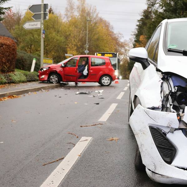 Ein beschädigter weißer Wagen steht nach einem Verkehrsunfall in Oberbantenberg mitten auf der Straße, der rote Unfall-Pkw im Hintergrund ist auf dem Fußgängerweg gefahren.
