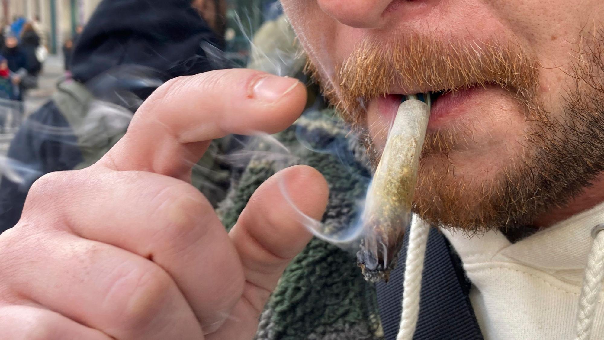 Ein Mann raucht auf einer Straße Marihuana.