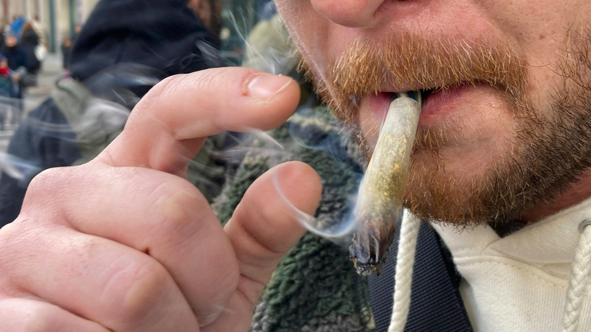 Ein Mann raucht auf einer Straße Marihuana.