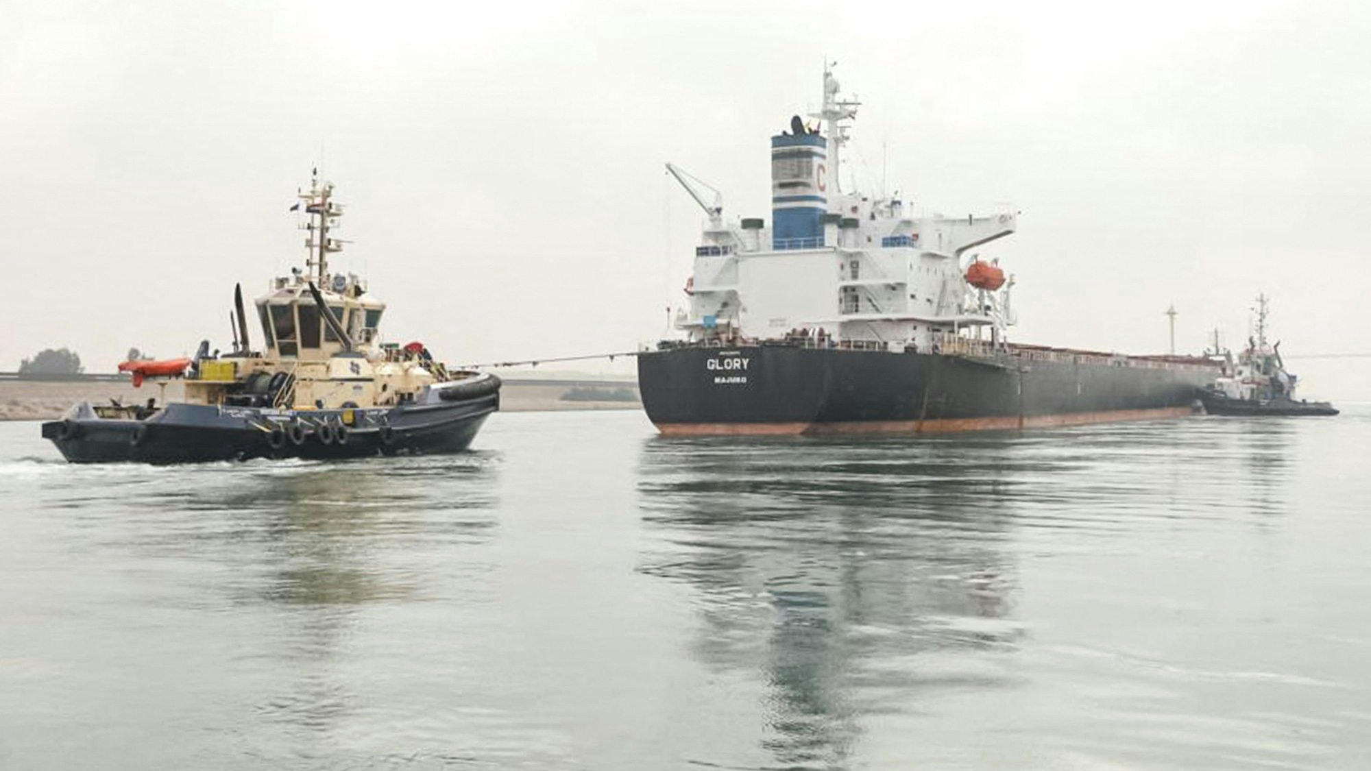 Das Frachtschiff „M/V Glory“ liegt auf einer Sandbank im Suezkanal und wird von einem anderen Schiff weggezogen.