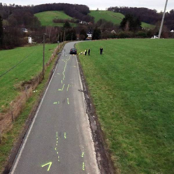 Ein Unfallaufnahmeteam der Polizei sichert Spuren auf einer Kreisstraße, auf der Kreidemarkierungen zu sehen sind.