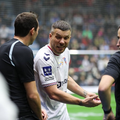 Lukas Podolski diskutiert mit den Schiedsrichtern.
