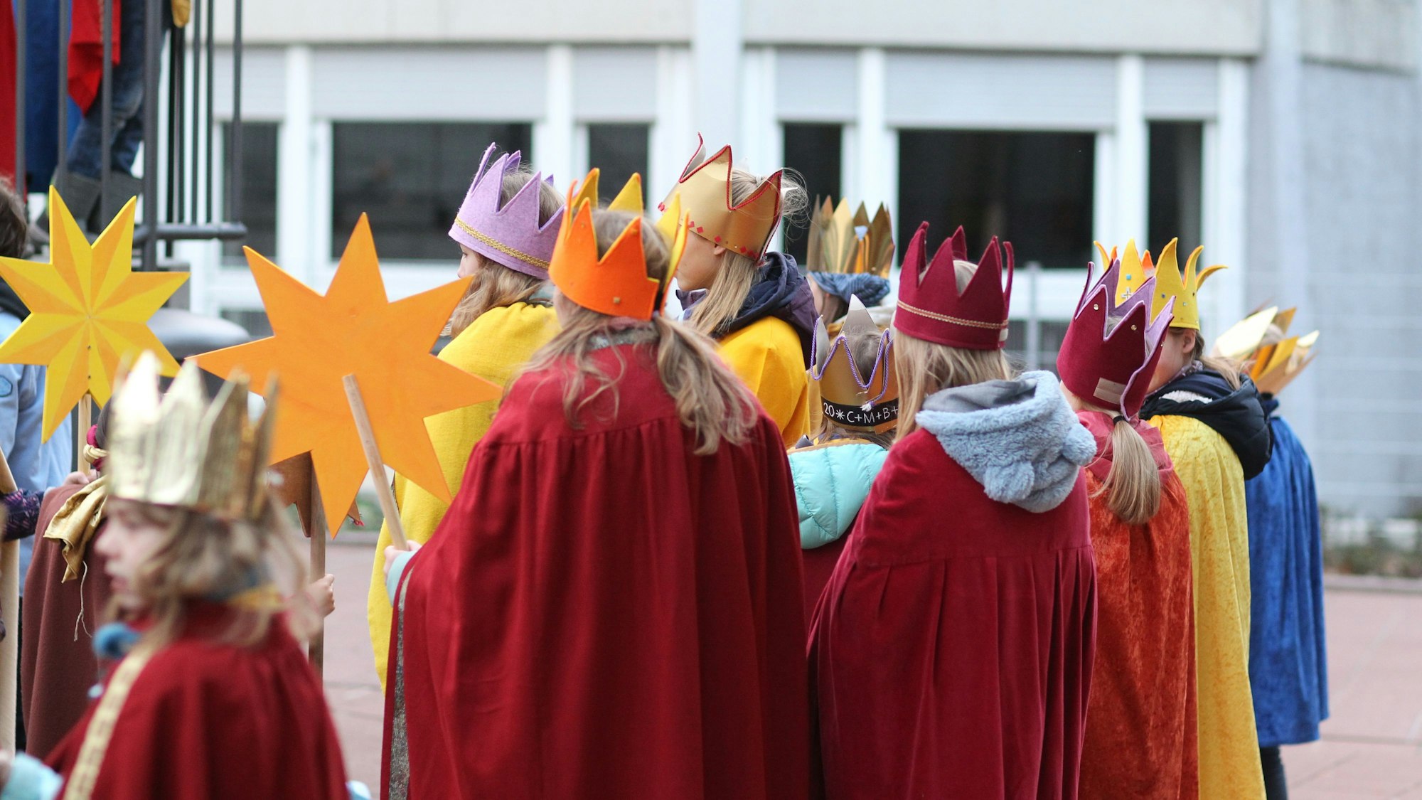 Eine Gruppe von Sternsingern steht auf einem Platz.