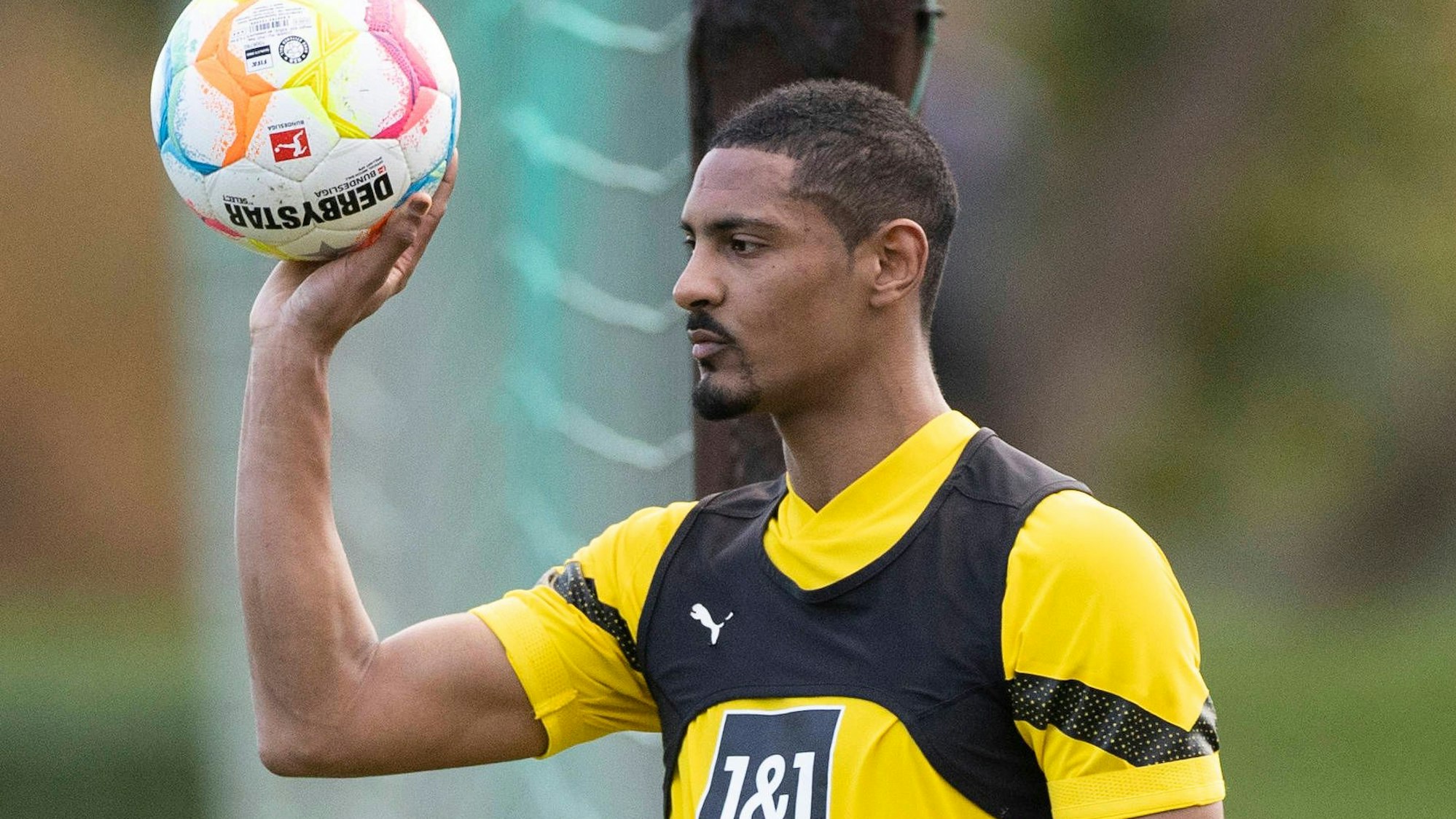 Sebastien Haller hält zwei Fußbälle in der Hand.