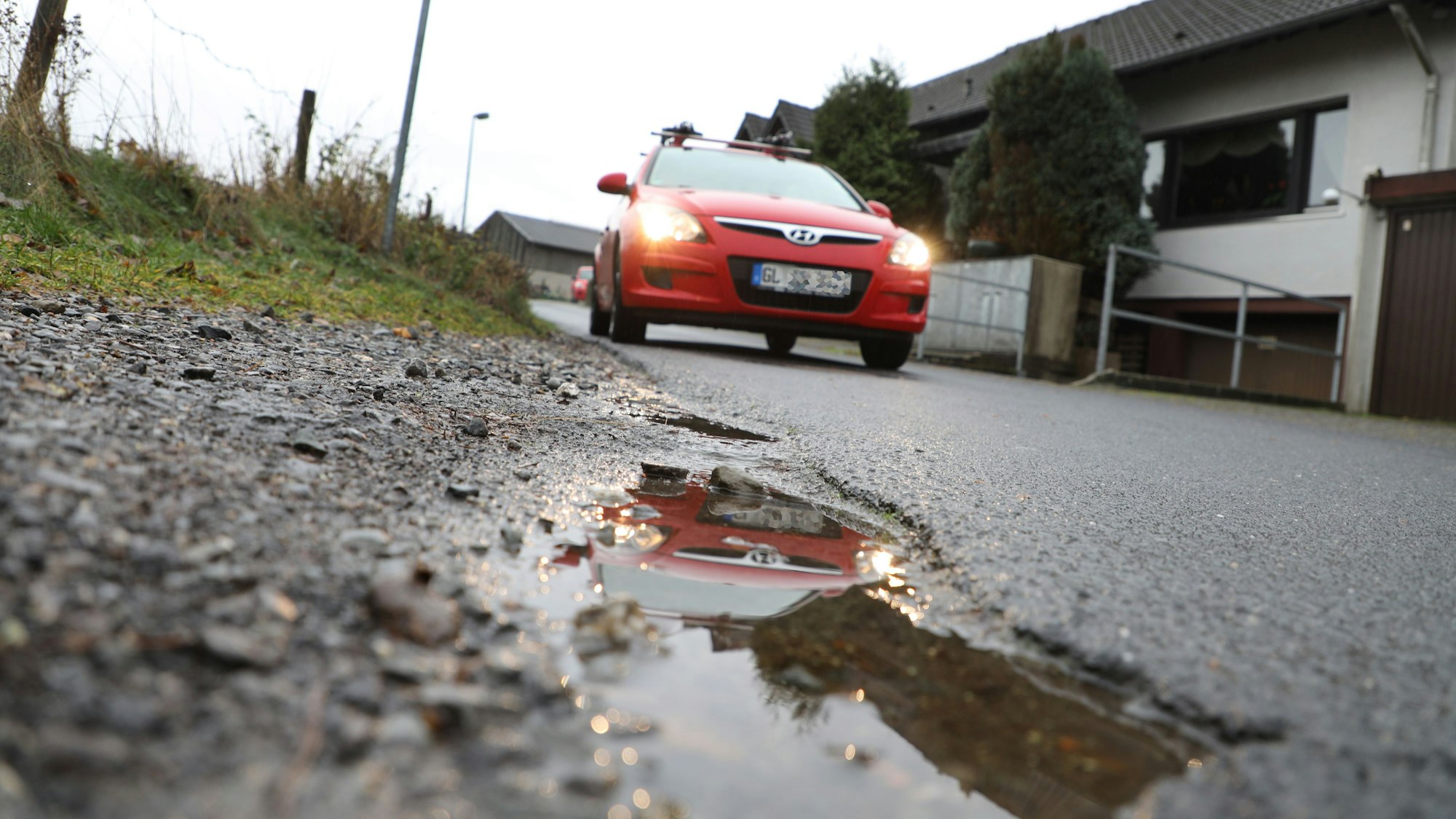 Ein Auto fährt auf einer Straße und spiegelt sich in einer Pfütze.