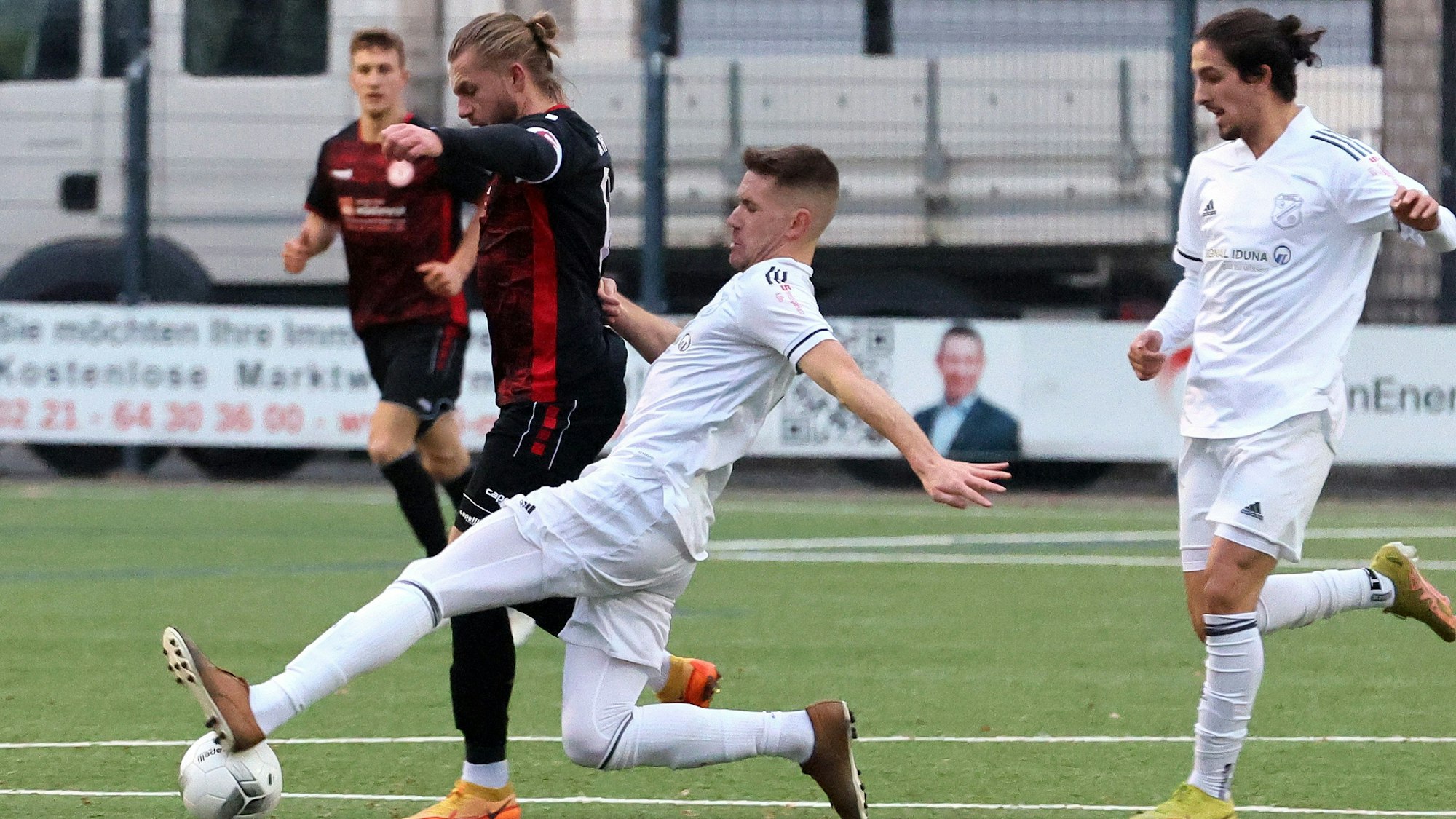 Ein Fußballspieler setzt im Zweikampf zu einer Grätsche an.