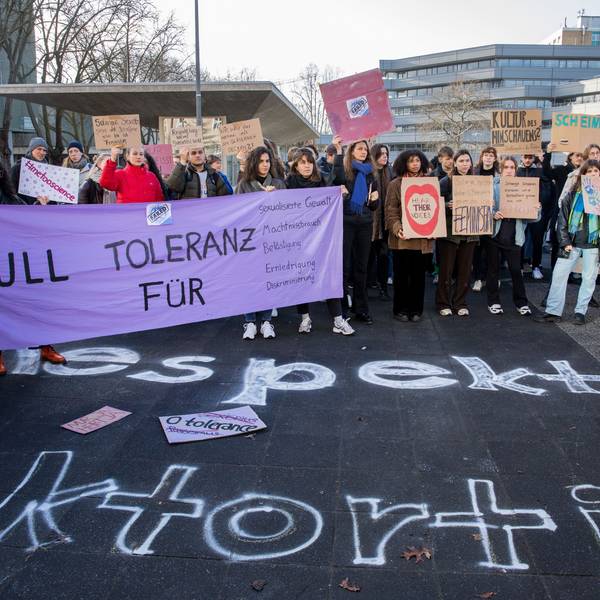 Etwa 250 Menschen demonstrieren auf dem Albertus-Magnus-Platz an der Uni Köln gegen sexualisierte Gewalt und halten Plakate in die Höhe.