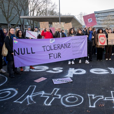 Etwa 250 Menschen demonstrieren auf dem Albertus-Magnus-Platz an der Uni Köln gegen sexualisierte Gewalt und halten Plakate in die Höhe.