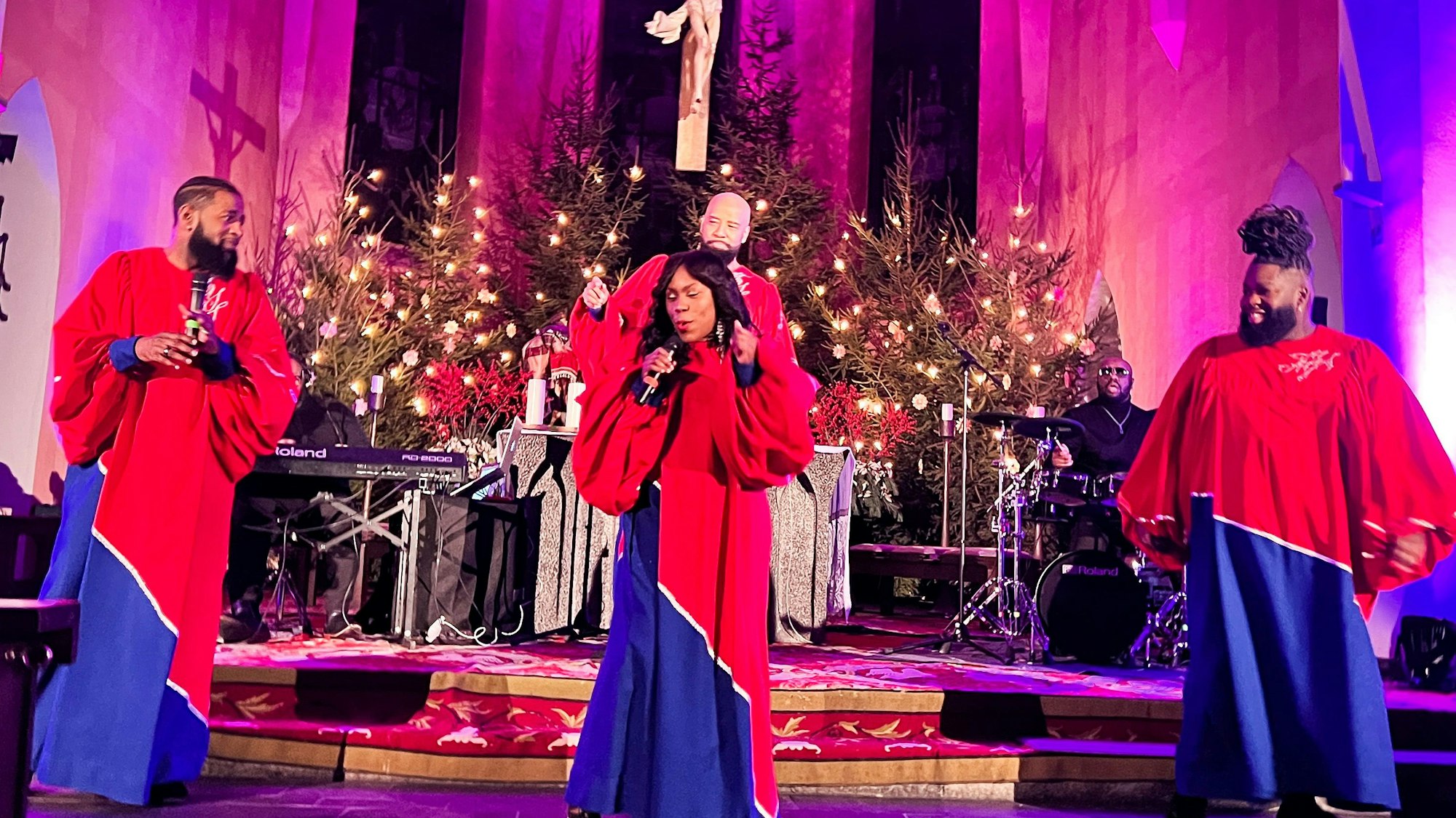 Vier Sängerinnen und Sänger in langen Gewändern stehen vor dem Altar in der Kirche St. Remigius und singen.
