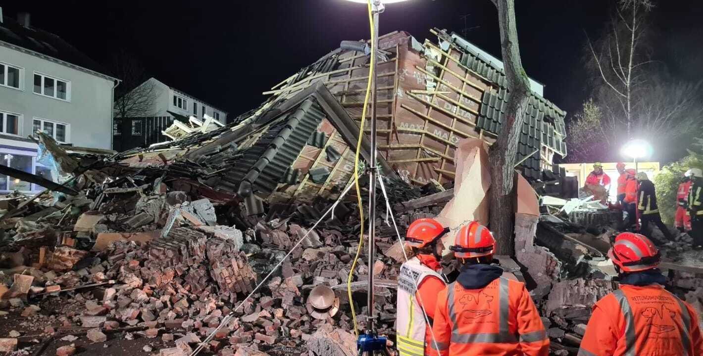 Feuerwehr und Rettungskräfte mit Spürhunden stehen vor einem eingestürzten Haus im Bochumer Stadtteil Linden.