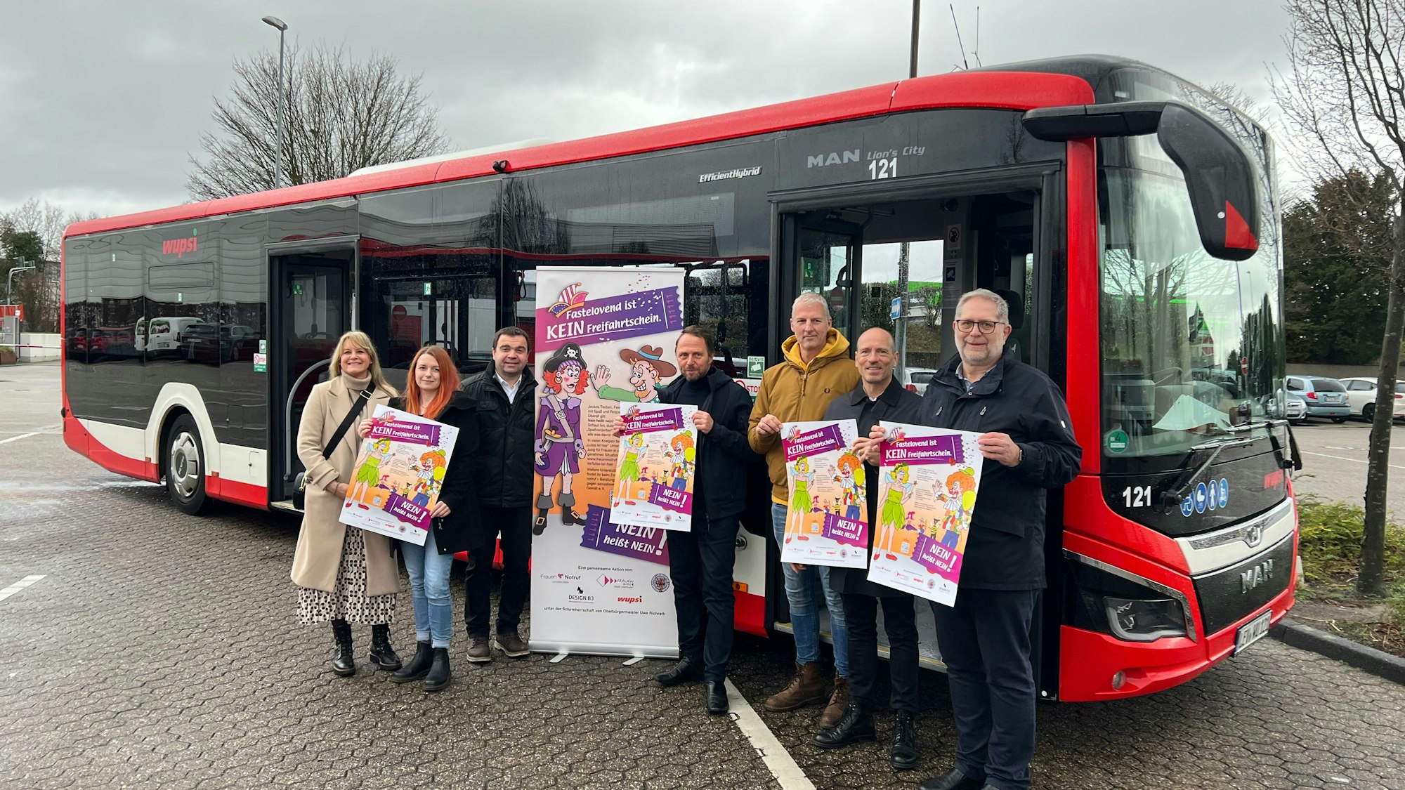 Vor einem Linienbus stehen sieben Personen und halten Plakate in die Luft.