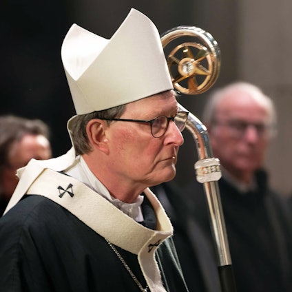 Der Kardinal Rainer Woelki zieht mit weißer Mitra, dem Bischofshut, und Hirtenstab zu einem Gedenkgottesdienst für den verstorbenen Papst Benedikt XVI. in den Kölner Dom ein. Im Hintergrund wird er von Gläubigen beobachtet.