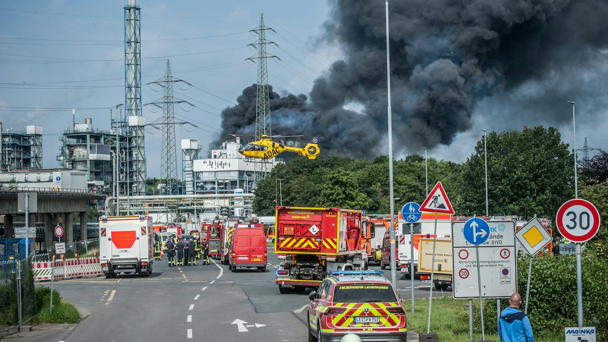 Feuerwehr, Rettungsfahrzeuge und ein Hubschrauber sind nach der Explosion in Bürrig vor der stark qualmenden Sondermüllverbrennung zu sehen