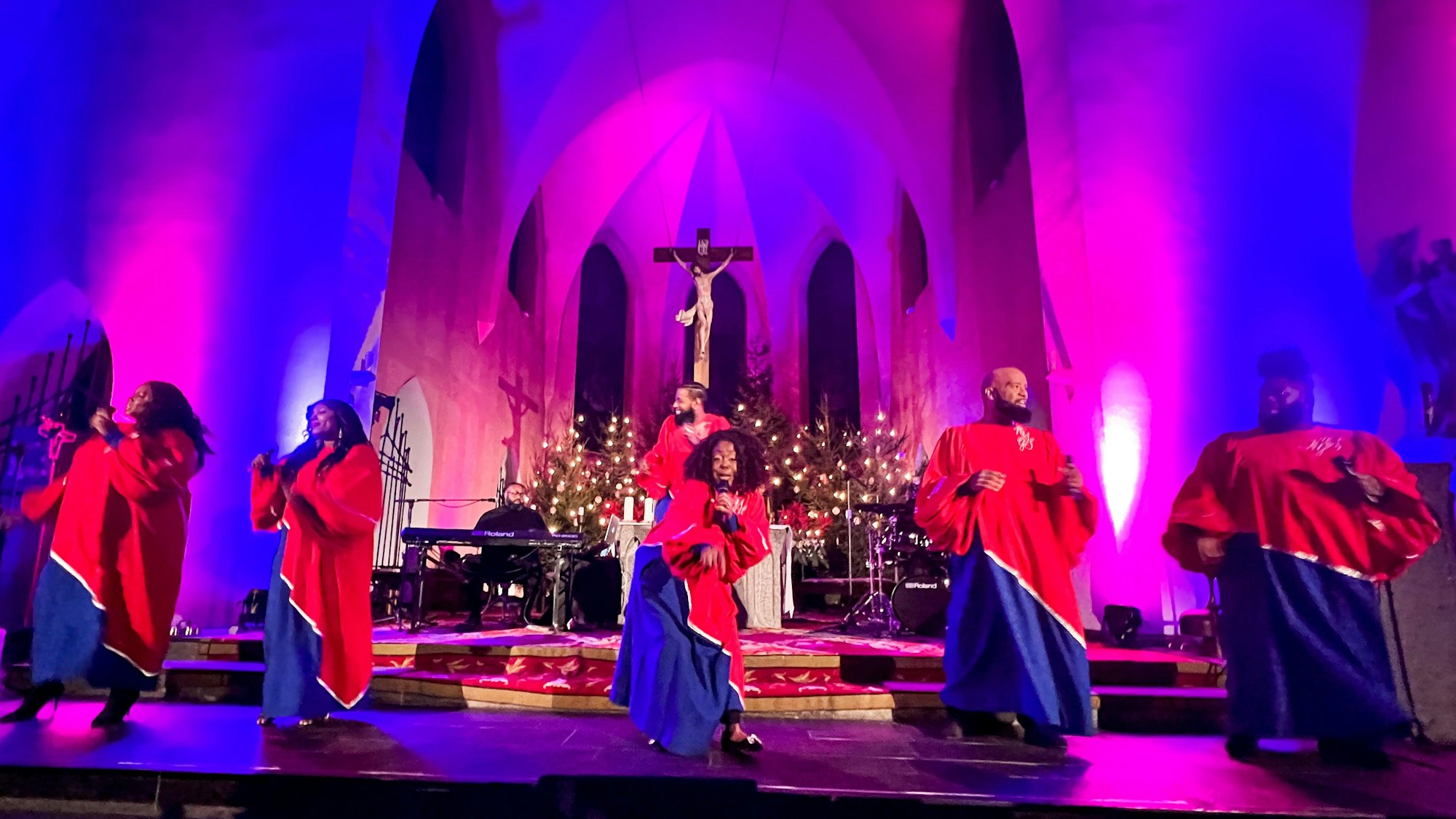 Sechs Sängerinnen und Sänger in langen Gewändern stehen vor dem Altar in der Kirche St. Remigius und singen.