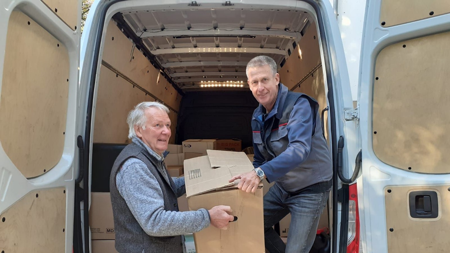 Wilhelm Stein (l.) und Ferdi Schwanitz verladen Kartons in einen Sprinter.