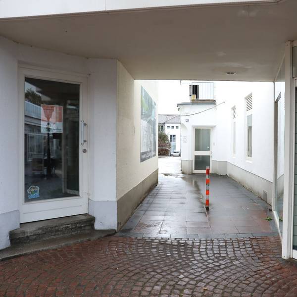 Ein schmaler Durchgang führt zwischen zwei Ladenlokalen hindurch.